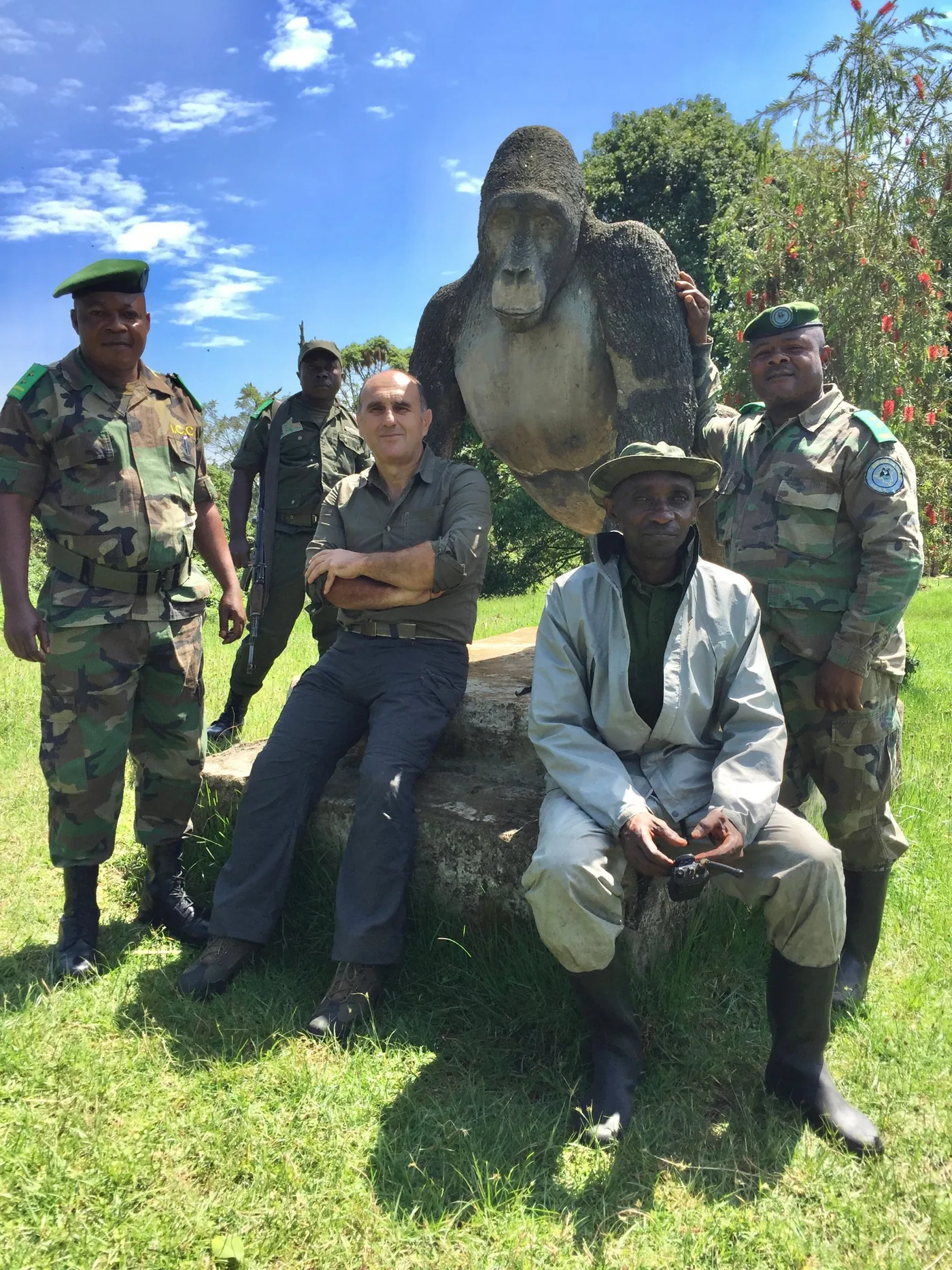 Fabrice Martinez assis avec quatre écogardes devant une statue de gorille