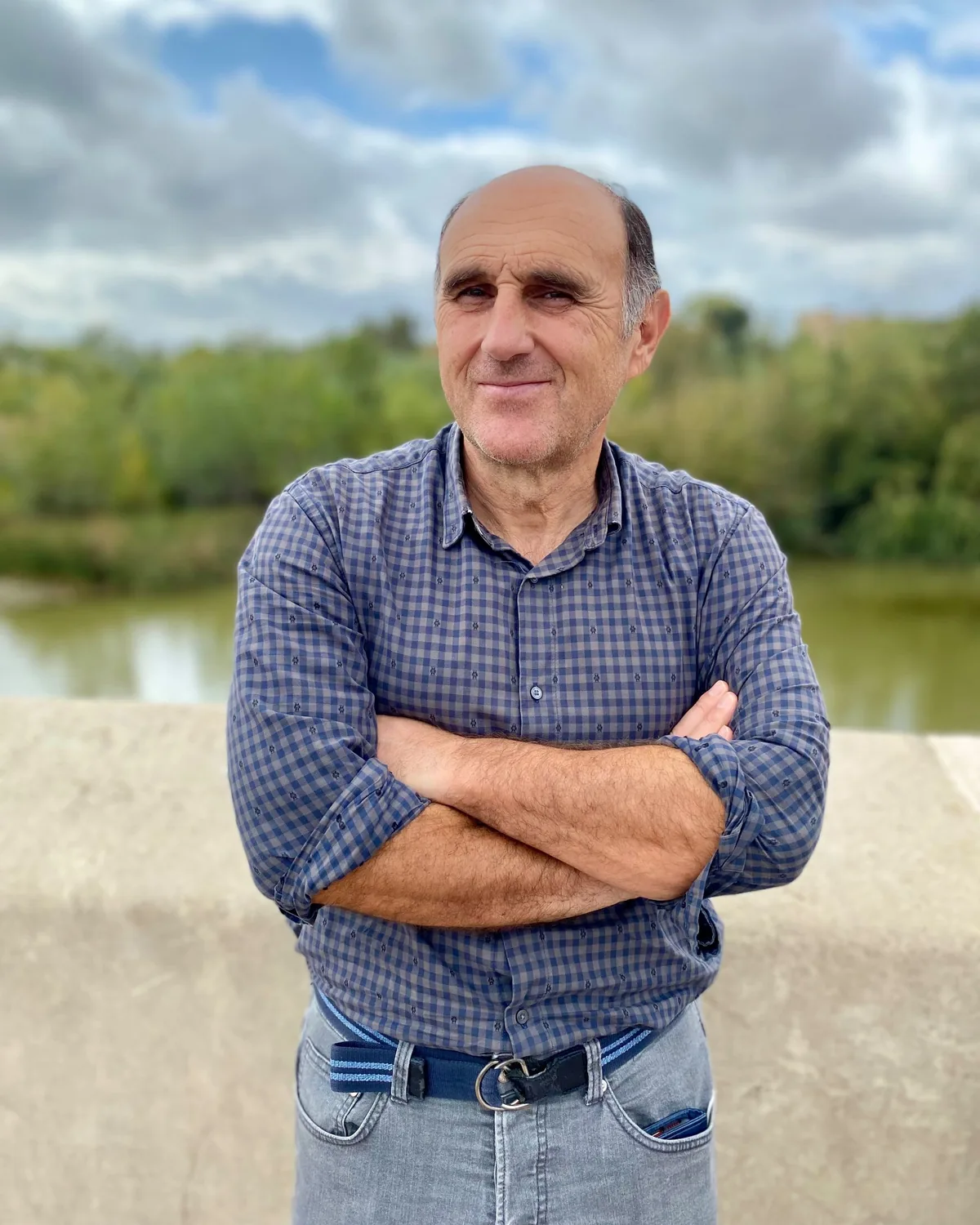 Portrait de Fabrice Martinez, bras croisés, au bord d'une rivière